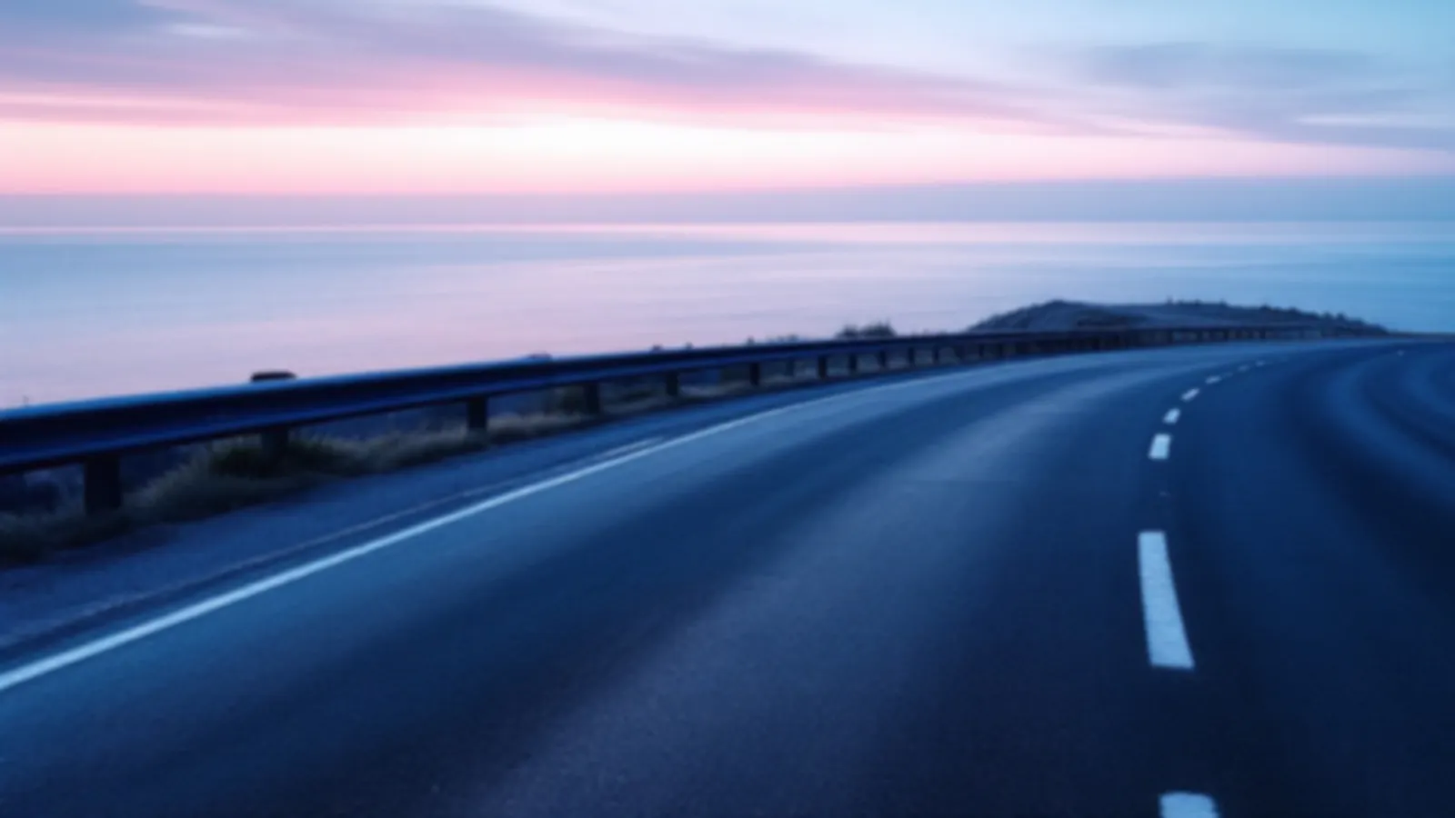 An empty coastal road curving above a calm blue sea at dawn, the GearboxRates view of find loan rates online, $100 – $5,000